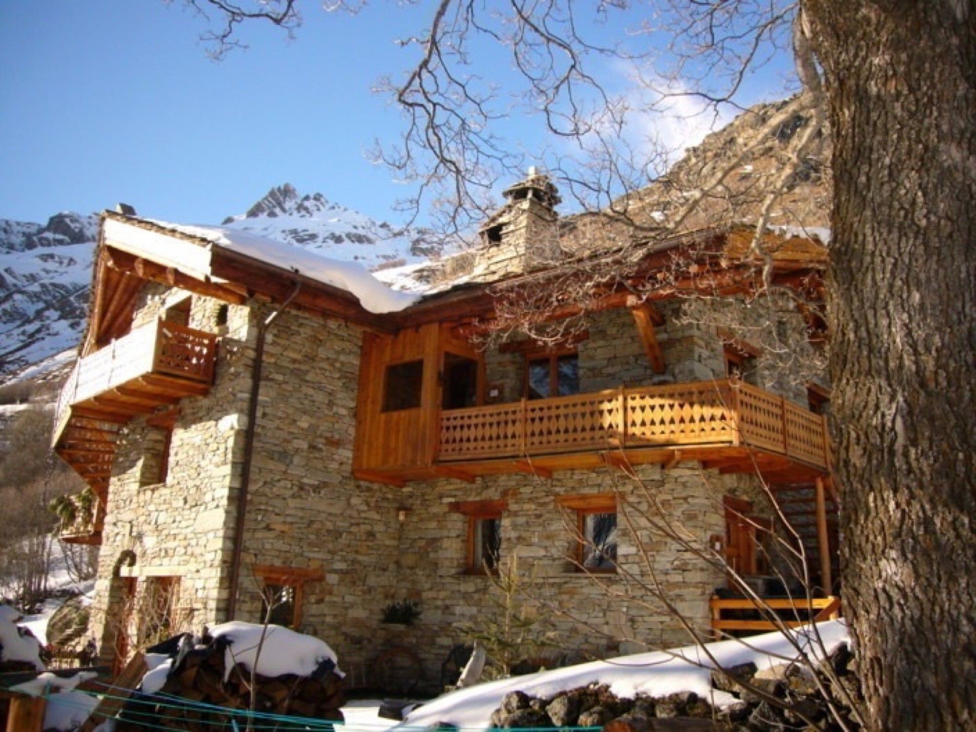 Ein Steinhaus mit Holzbalkonen und einem verschneiten Berggrund.