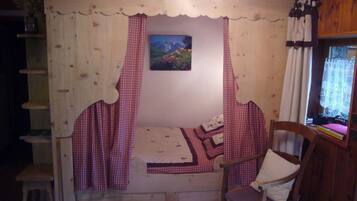 Een knus ingerichte kamer met een bed, een stoel, een schilderij en een raam met gordijnen.