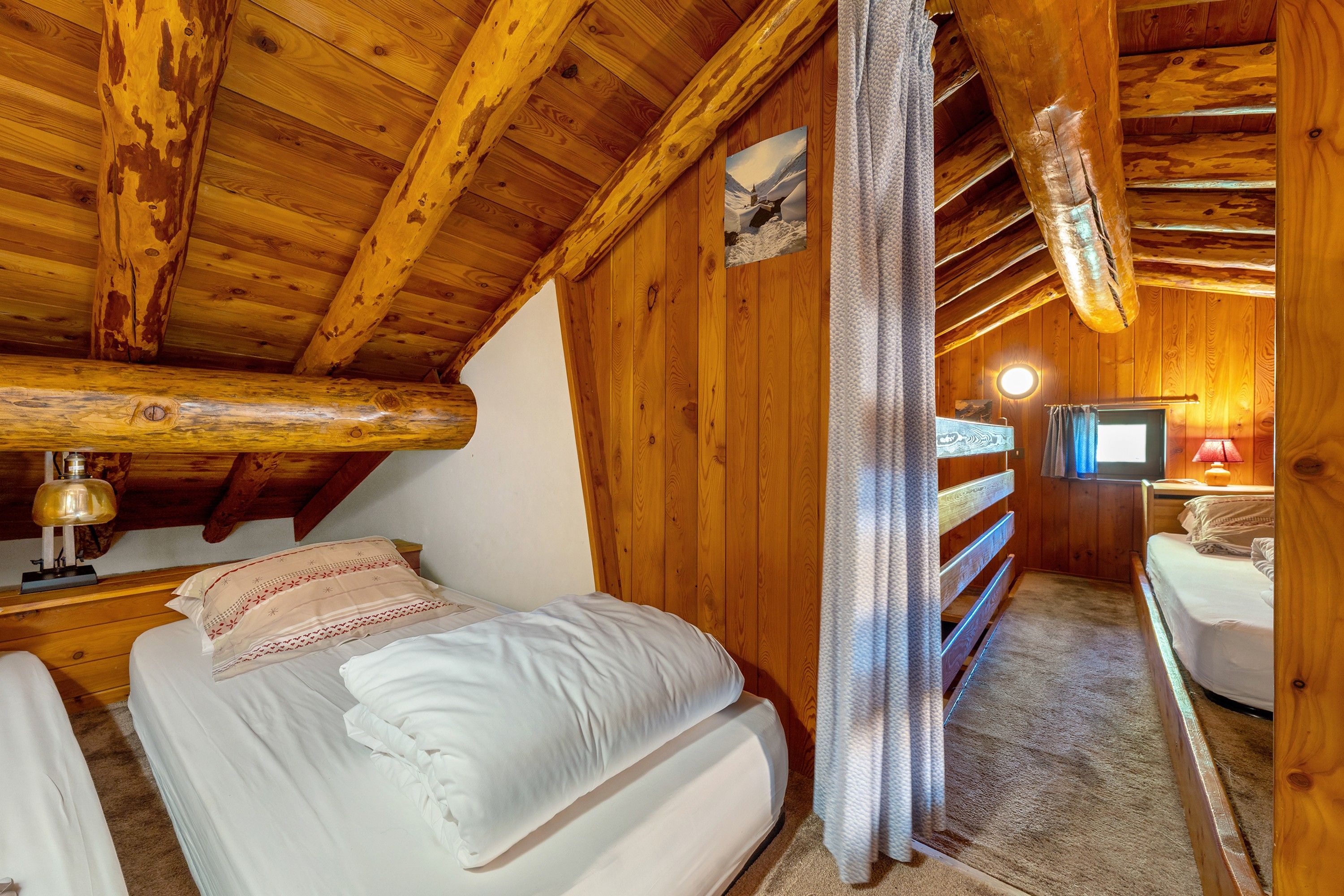 Une chambre confortable, aménagée dans un chalet en bois, avec un lit, une télévision et une lampe.