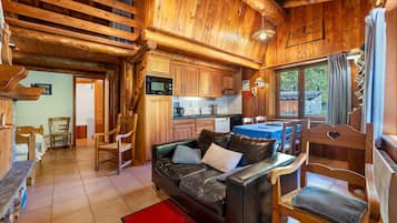 A cozy cabin interior with a wooden interior, a leather sofa, and a dining area.