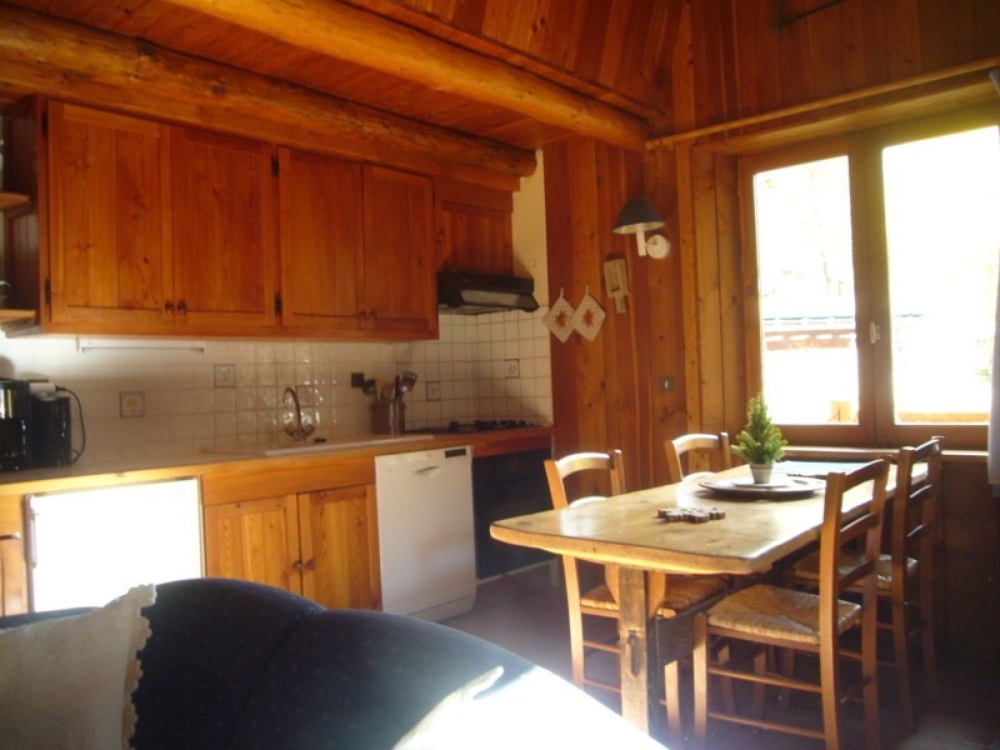 Interior de una cabaña de madera con cocina, mesa de comedor y sillas.
