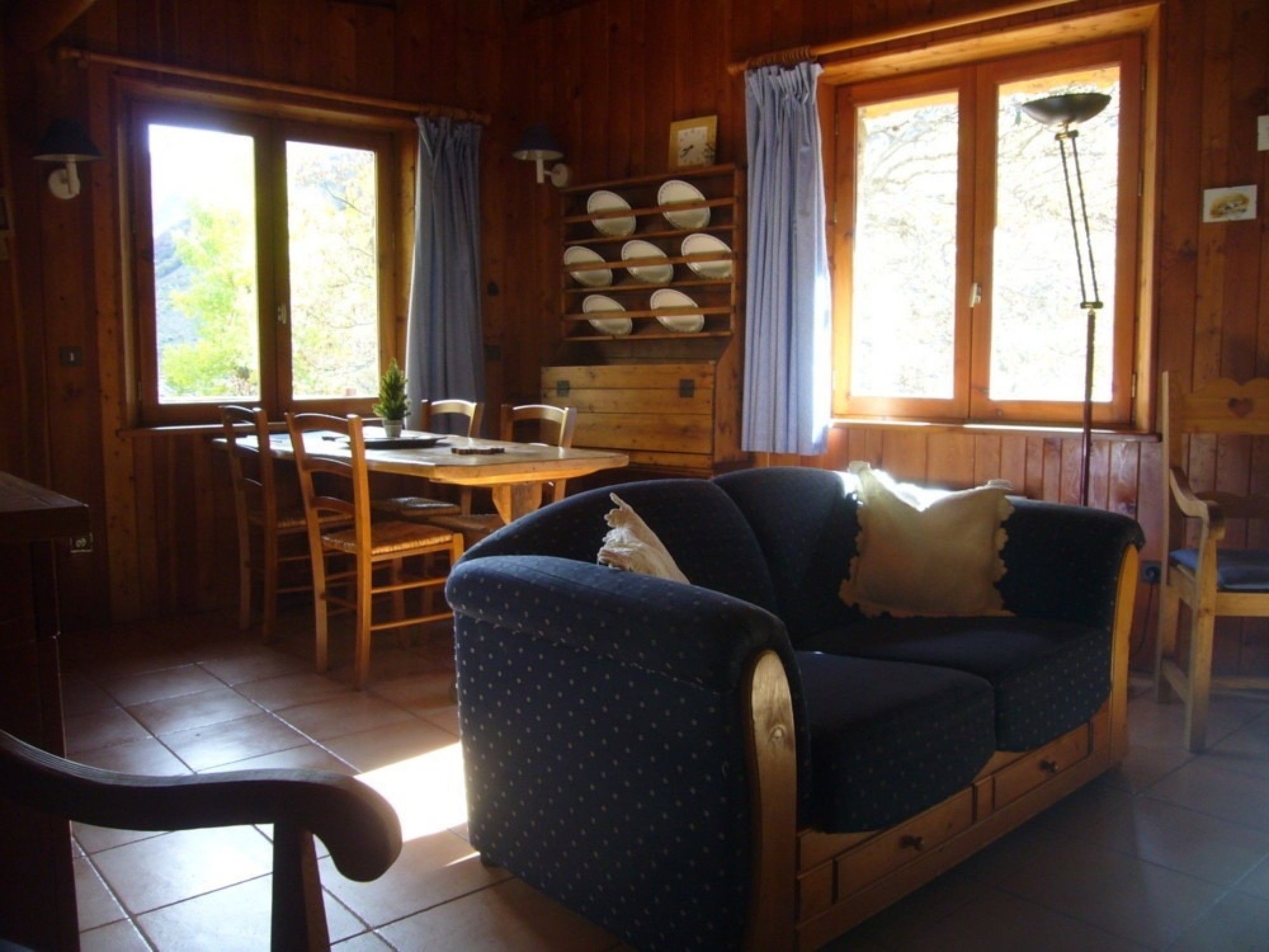 Ein Holzblockhaus-Interieur mit Essbereich, einer Couch und einer Lampe.