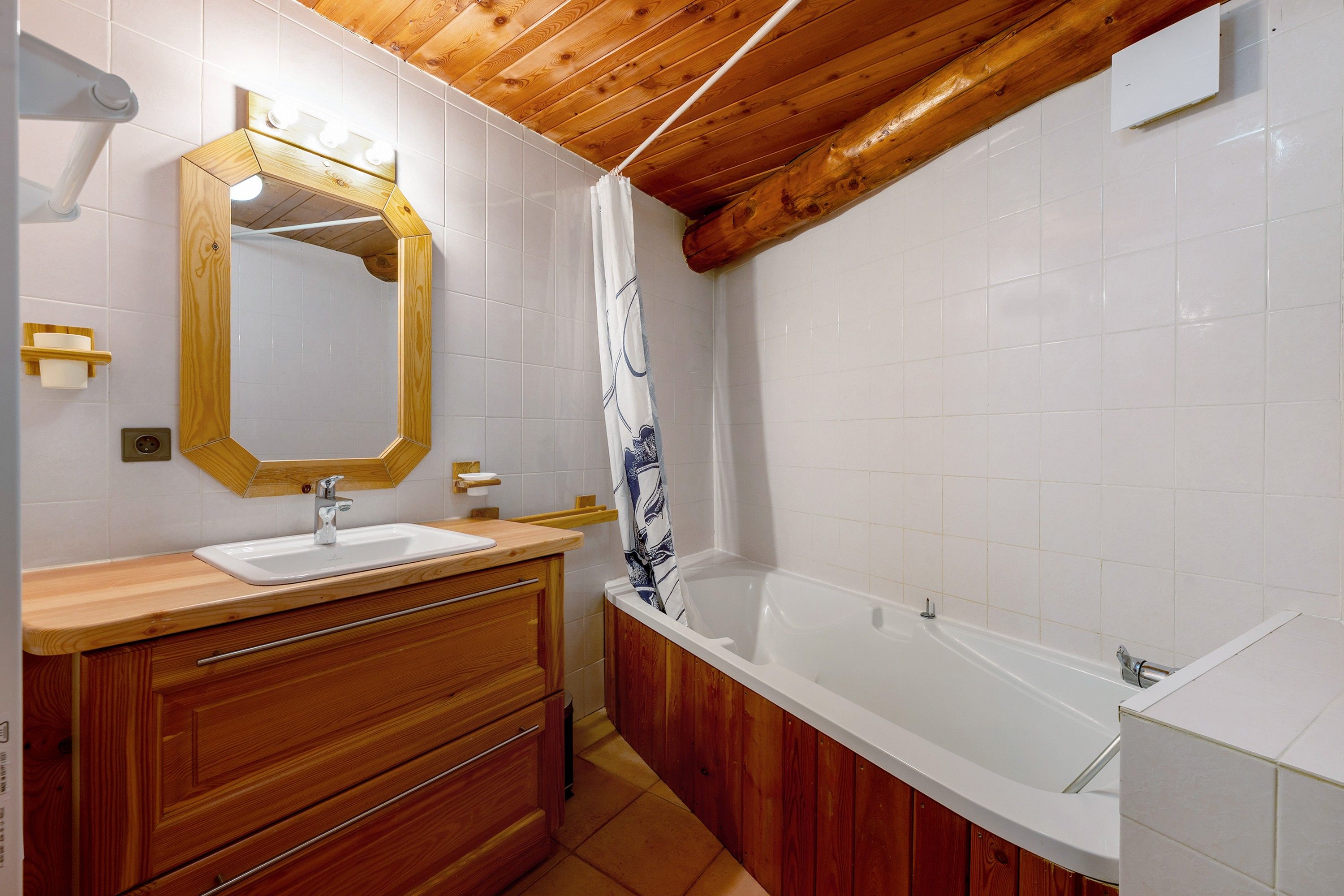 Ein Badezimmer mit einem Holzbadschrank, einem Waschbecken, einem Spiegel, einer Duschvorhang und einer Badewanne.
