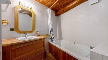 Ein Badezimmer mit einem Holzbadschrank, einem Waschbecken, einem Spiegel, einer Duschvorhang und einer Badewanne.