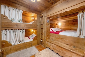A wooden cabin with bunk beds, a small bathroom, and a wooden ceiling.