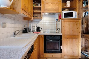 A compact kitchen with wooden cabinets, a built-in oven, a microwave, and a coffee maker. - Gîte l'Erablo – Chalet Les Abeillos in Bonneval-sur-Arc, Vanoise National Park (Bonneval-sur-Arc)