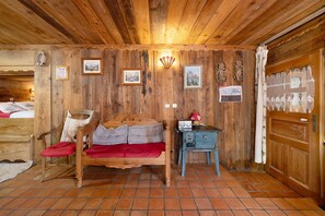 A wooden room with a bed, a small table with a radio, and a wall with framed pictures. - Gîte l'Erablo – Chalet Les Abeillos in Bonneval-sur-Arc, Vanoise National Park (Bonneval-sur-Arc)