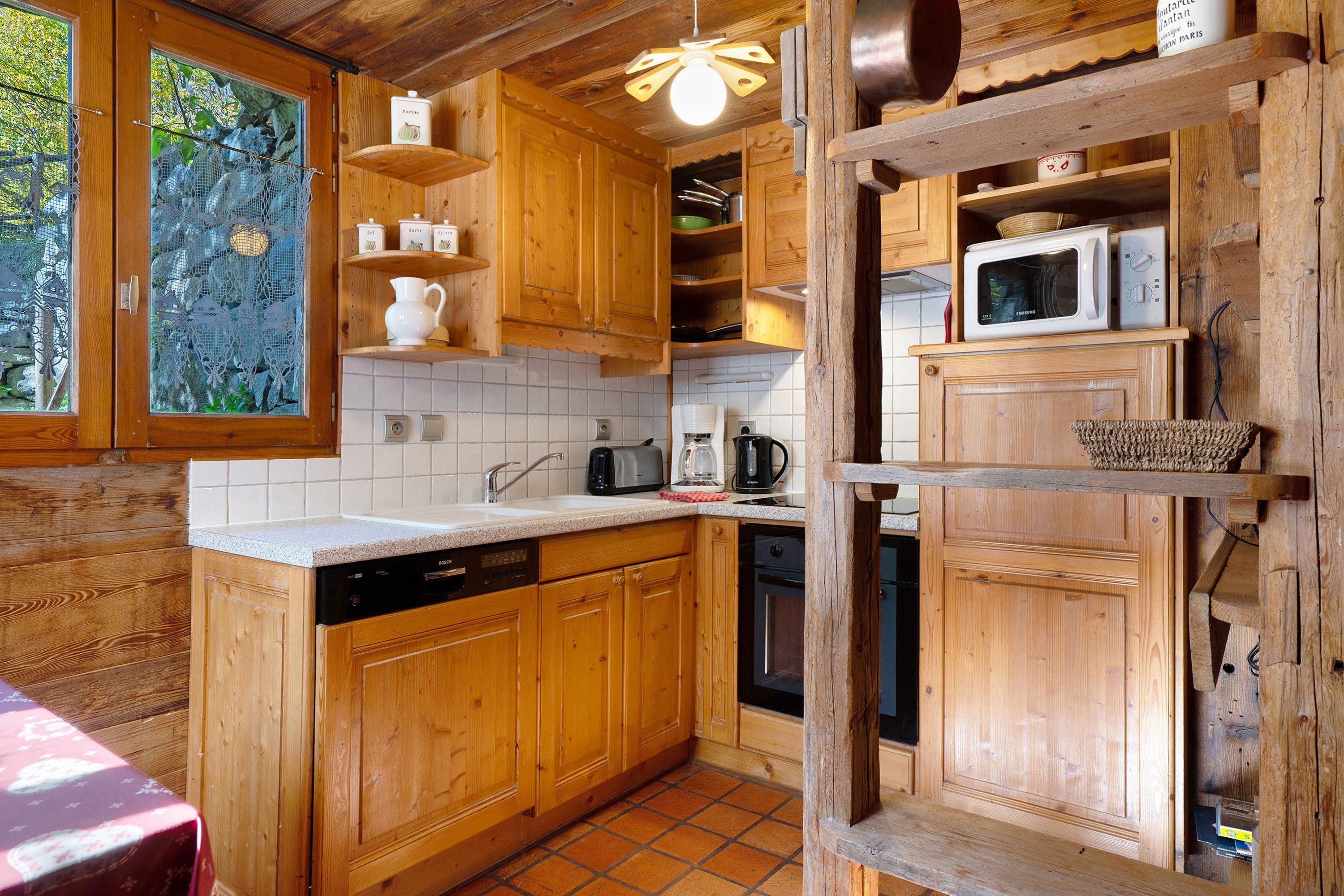 Une cuisine rustique, aménagée dans une cabane en bois, avec un évier, une cuisinière et des placards.