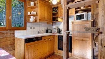 Une cuisine rustique, aménagée dans une cabane en bois, avec un évier, une cuisinière et des placards.