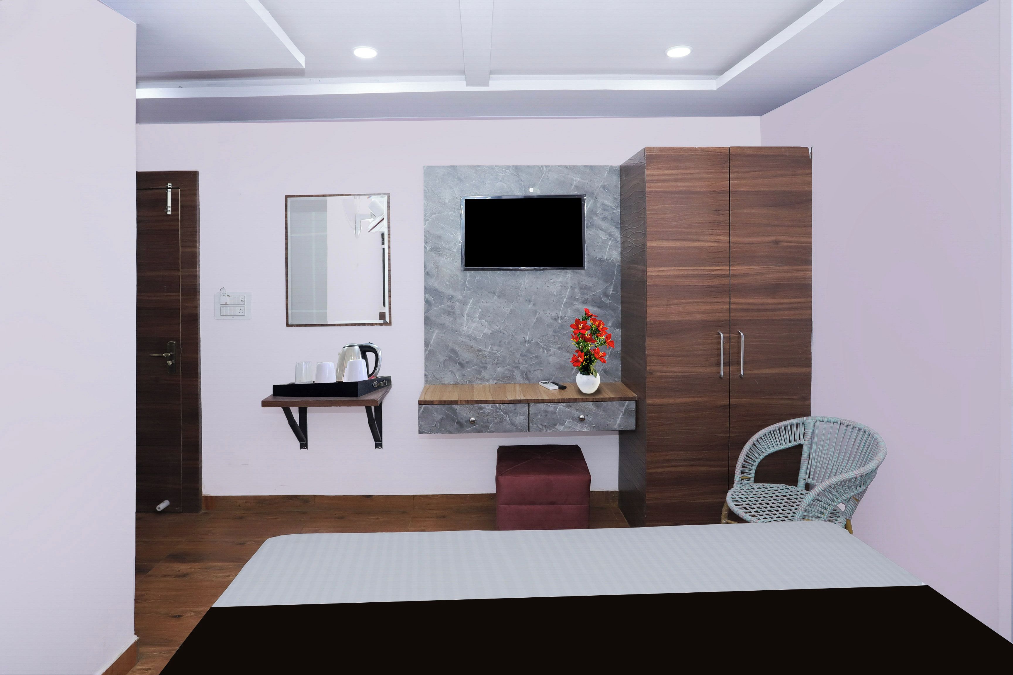 A modern bedroom with a bed, a wooden wardrobe, a vanity with a mirror, a television, and a wicker chair.