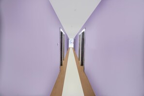 A long hallway with purple walls and a white floor, leading to a door at the end. - Townhouse Rauniyar City Centre Ratu Road (Ranchi)