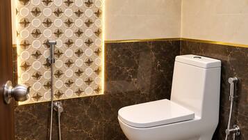 Un baño moderno con inodoro, ducha y un estante de vidrio con artículos de aseo.