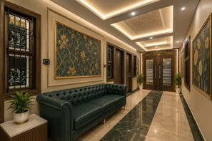 A hotel lobby with a dark green sofa, a large floral painting, and a marble floor. - Gorakhpuriya Hotel (Bilaspur)