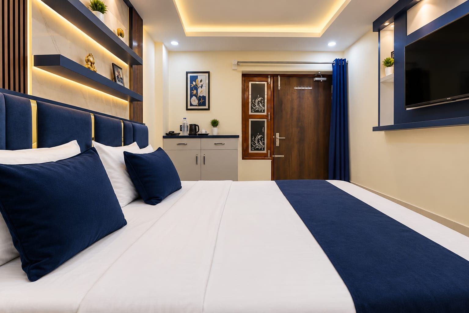A modern bedroom with a large bed, bedside tables, a TV, and a wardrobe.