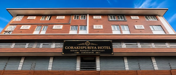 Un edificio de hotel con un cartel que indica que ofrece habitaciones, un salón de banquetes y un restaurante.
