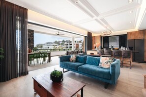 Ein modernes Wohnzimmer mit einem blauen Sofa, einem Holztisch und einem Essbereich mit grünen Stühlen.