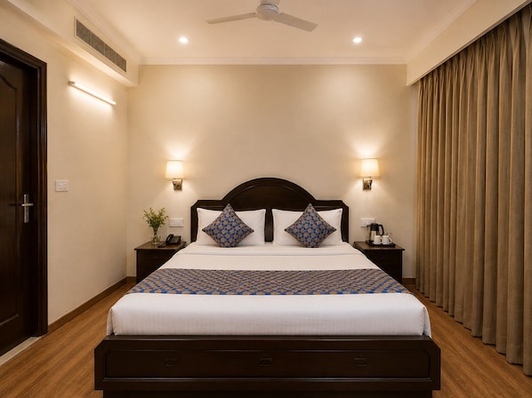 A hotel room with a bed, bedside tables, a ceiling fan, and a window with curtains.