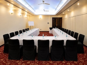 A conference room with a long table, black chairs, water bottles, and a whiteboard.