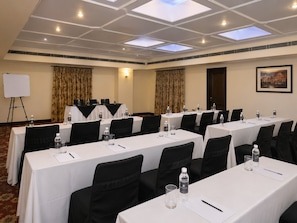 A conference room with multiple tables, chairs, and a whiteboard.