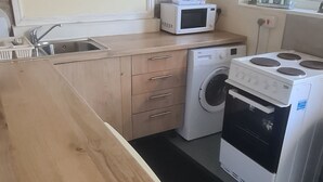 Cocina compacta con encimera de madera, microondas, lavadora y estufa.
