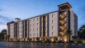 Un hotel de varios pisos con fachada simétrica, amplias ventanas y una escalera central.