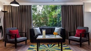 Quarto com sofá preto, duas poltronas, mesa de centro e tapete colorido.