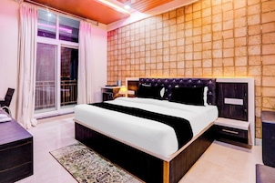 A modern hotel room with a large bed, a nightstand, a desk, and a view through a sliding door.