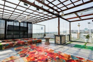 A spacious room with a large window, a patterned floor, and a seating area.