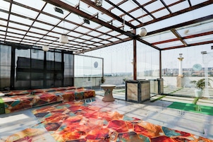 A spacious room with a large window, a patterned floor, and a seating area.