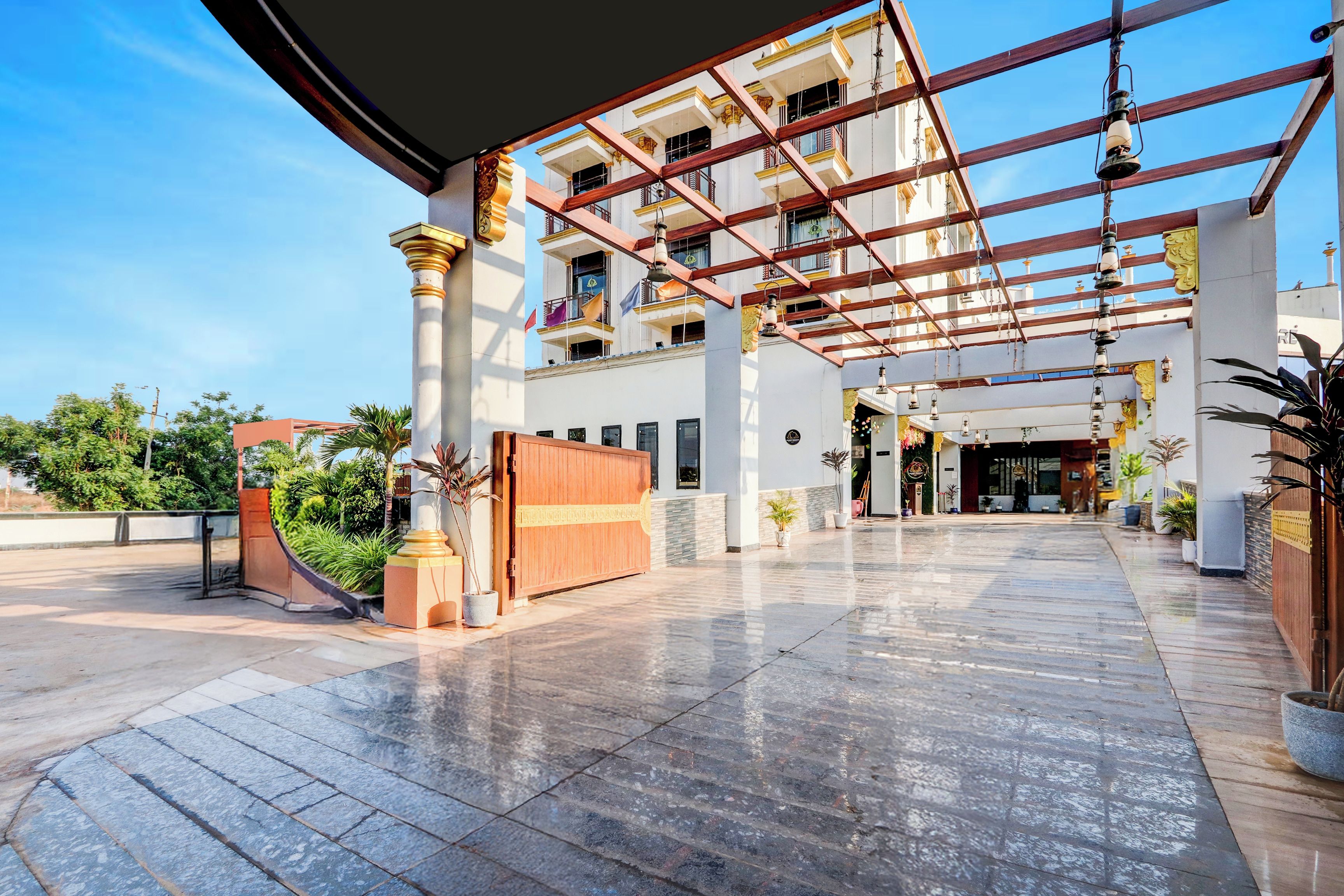 A spacious hotel entrance with a covered walkway, a large open area, and a building with multiple balconies.