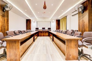 A conference room with a long wooden table, multiple chairs, and ceiling fans.