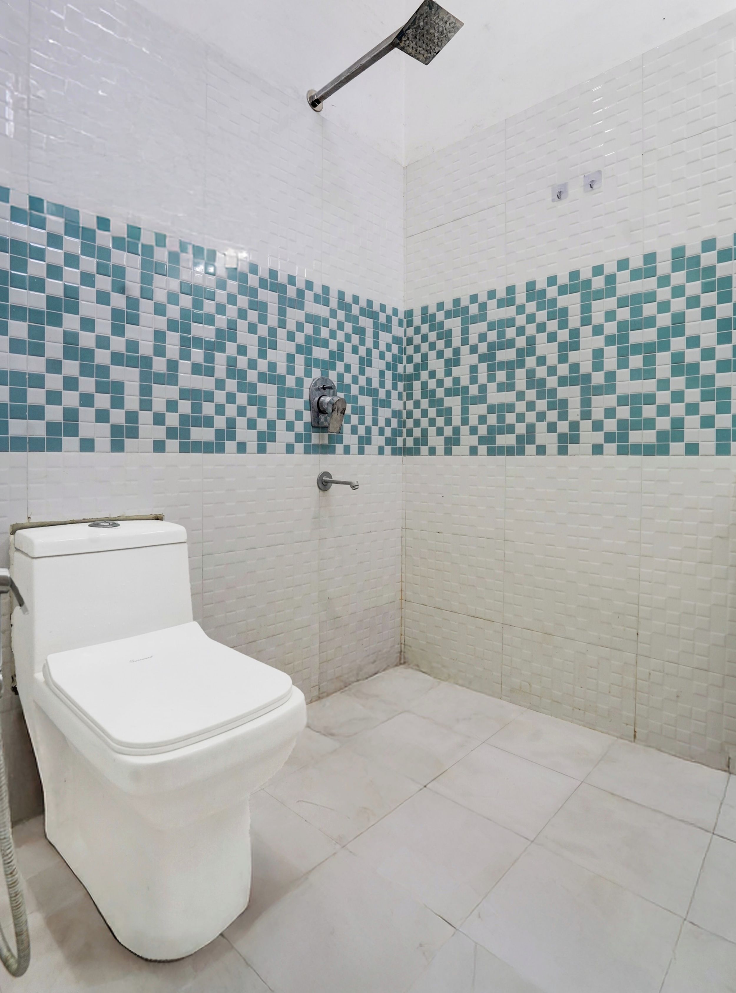 Un baño con inodoro, ducha y paredes con azulejos.