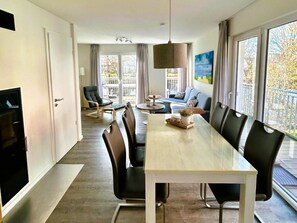 A modern dining area with a long table, chairs, and a central light fixture. - House No. 33, Holiday Home Deichgraf (Wangerland)