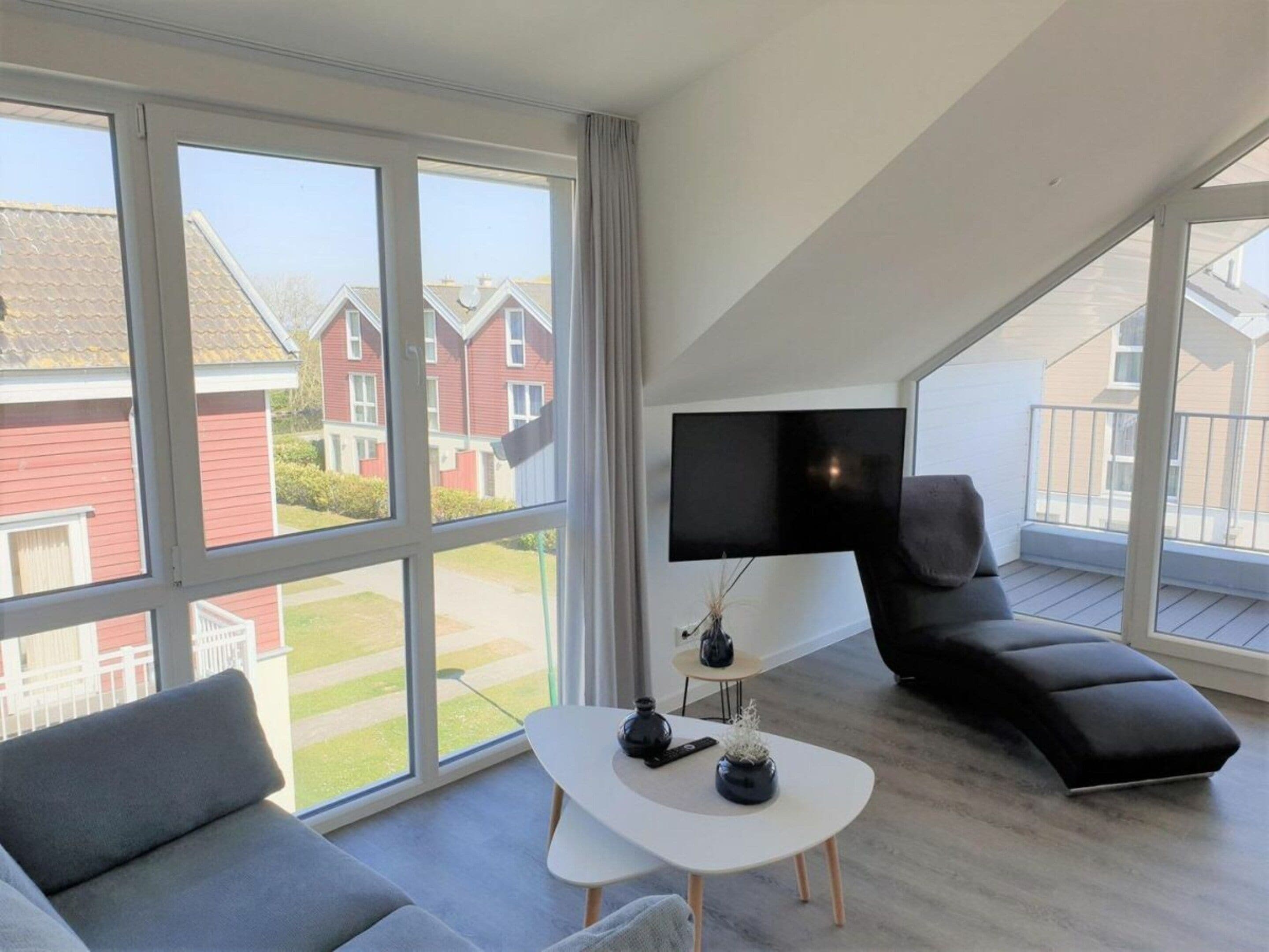 A modern living room with a large window, a flat-screen TV, a sofa, and a coffee table.