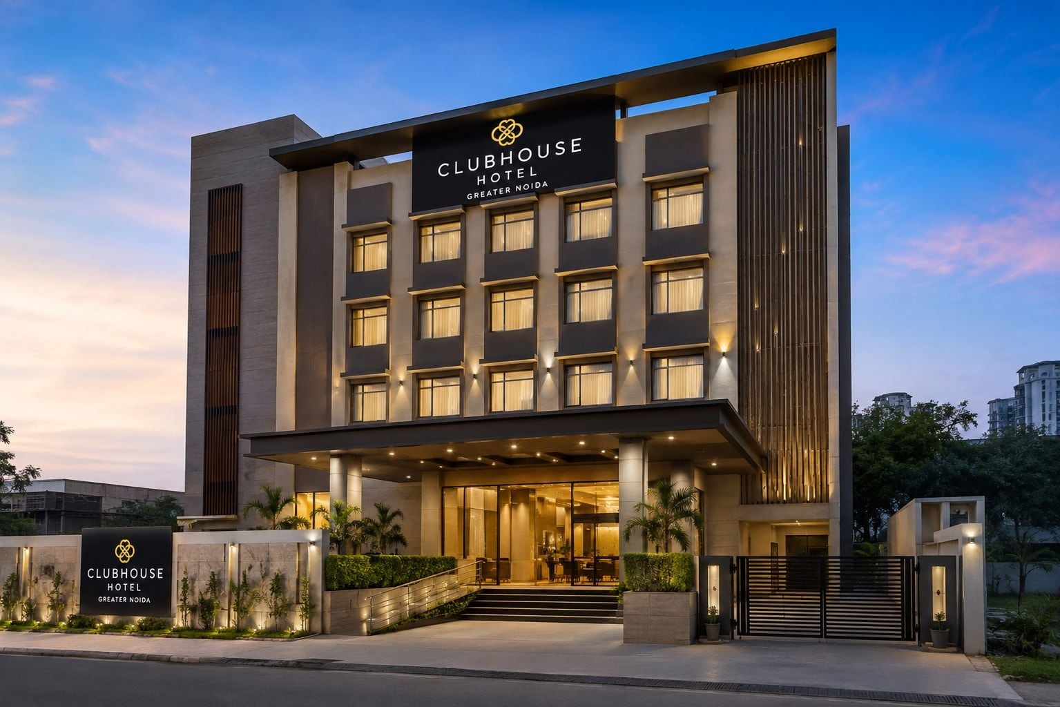 En moderne Clubhouse Hotel bygning med en markant indgang, mange vinduer og en veloplyst facade.