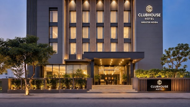 Edifício moderno do Clubhouse Hotel, com entrada destacada, grandes janelas e fachada bem iluminada.