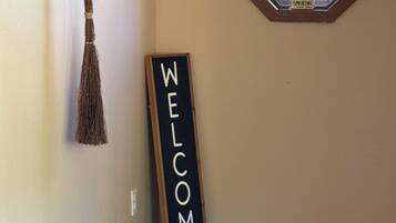 A room with a welcome sign, a broom, a window, and a wooden bench.