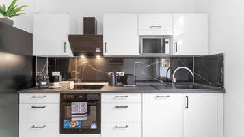 A modern kitchen with white cabinets, a built-in microwave, a coffee machine, and a kettle.