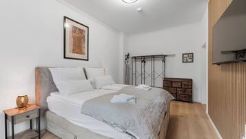 A modern bedroom with a bed, bedside table, and a wall-mounted shelf.