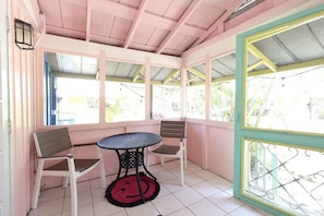 A covered patio area with a table and two chairs, a tiled floor, and a view through the open sides. - BlueDolphin Cottage Walk To Siesta Beach (Siesta Key)