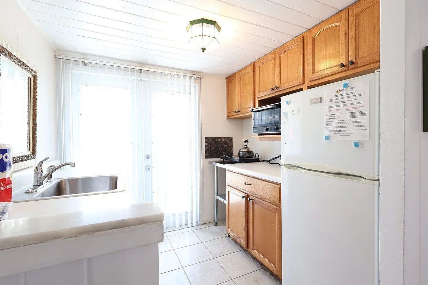 A kitchen with a sink, stove, microwave, and refrigerator.