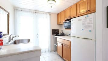 A kitchen with a sink, stove, microwave, and refrigerator.