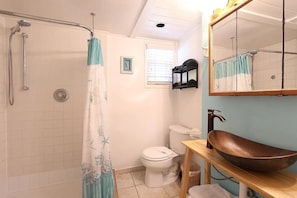 A bathroom with a shower, toilet, and a sink with a mirror.