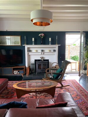 A living room with a fireplace, leather sofa, and a glass coffee table. - Large home, 6 bedrooms, private parking, gardens (Barnstaple)