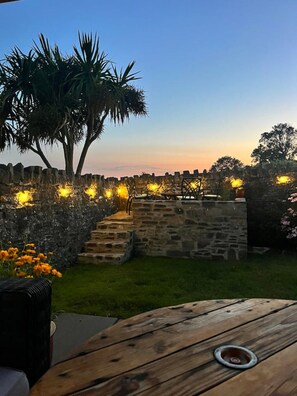 Un espace extérieur aménagé avec des murs en pierre, une table en bois et une vue sur le ciel.