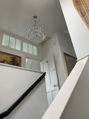 Un escalier avec une rampe blanche et un lustre au-dessus.