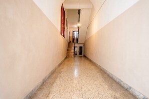 A corridor with a marble floor, a staircase at the end, and a hanging light fixture. - Ravanas City Escape | Stylish 2BR Apartment (Bari)