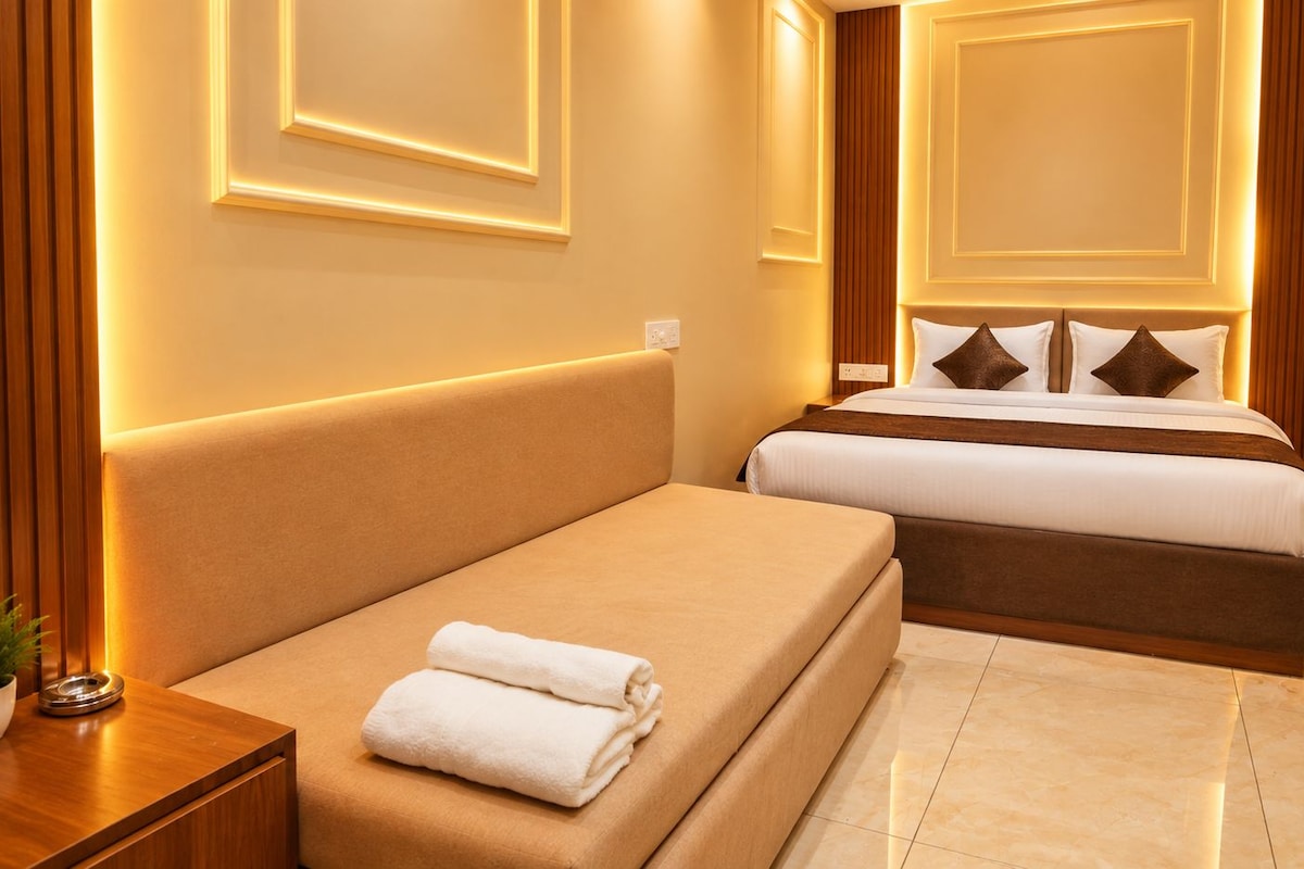 A hotel room with a bed, bedside table, and a potted plant.