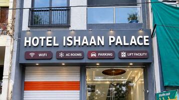 A hotel named 'Hotel Ishaan Palace' with a signboard indicating amenities like WIFI, AC rooms, parking, and lift facility.