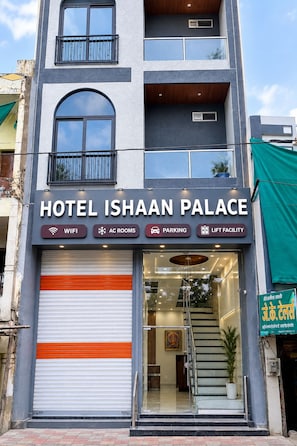 A hotel named 'Hotel Ishaan Palace' with a signboard indicating amenities like WIFI, AC rooms, parking, and lift facility. - Hotel Ishaan Palace (Ujjain)
